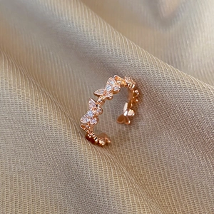 Close-up of rose gold butterfly ring with pave-set zircon crystals on champagne silk