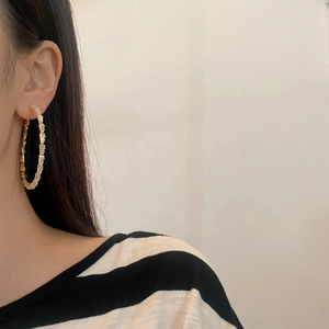 Gold-plated large hoop earrings with shimmering crystals on model in side view