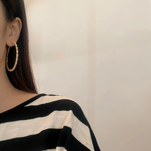 Elegant gold-tone large hoop earrings featuring sparkling pave-set zircons on a model