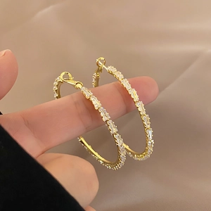 Detail der goldenen Creolen mit einer Reihe von Zirkonia-Kristallen im Baguette-Schliff