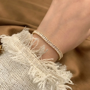 Elegant gold bracelet featuring sparkling rectangular zircon stones on a female wrist