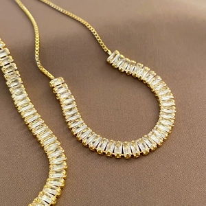 Detailed macro view of gold adjustable box chain and rectangular cubic zirconia settings