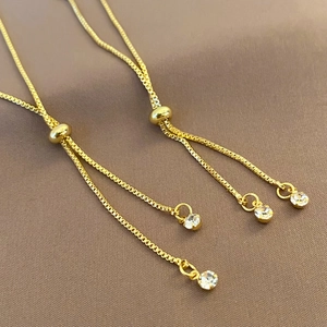 Detail of adjustable gold-plated box chains with sparkling zircon charms and beads