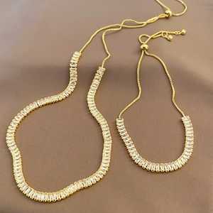 Adjustable zircon necklace and bracelet set in gold finish on silk background