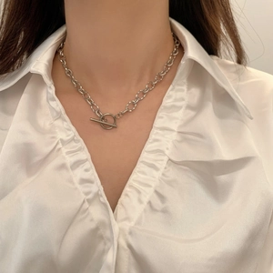 Gros plan d'un collier chaîne argentée avec fermoir à bascule OT porté par un mannequin