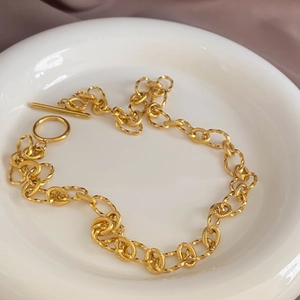 Détail du collier à grosse chaîne dorée avec texture spirale et fermoir OT