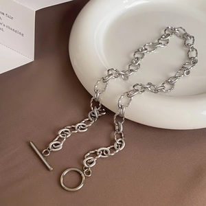 Détail du collier à fermoir à bascule argenté avec maille torsadée sur un support esthétique