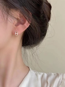 Close-up of gold chain link earrings with pavé crystals worn by a model