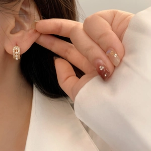 Elegant gold U-shaped earrings with pearls and micro-pave crystals on the model