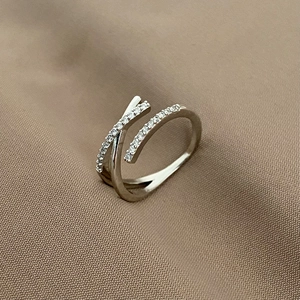Dettaglio ravvicinato di un anello incrociato in argento con zirconi su tessuto