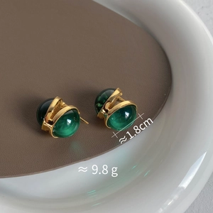Détail macro de boucles d'oreilles en verre vert émeraude avec base couronne dorée