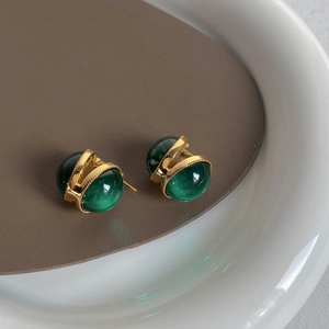 Détail de boucles d'oreilles vintage en verre émeraude avec monture en métal doré poli