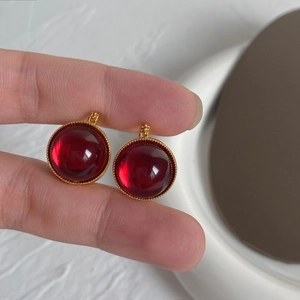 Détail du pendentif en verre rubis avec bord perlé doré et texture transparente