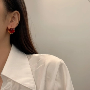 Boucles d'oreilles dorées rétro avec pierres rouges sur mannequin en chemise de satin