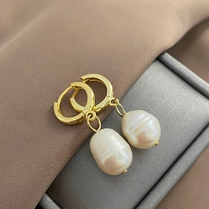 Detail of baroque freshwater pearl earring with gold plated hoop on brown silk