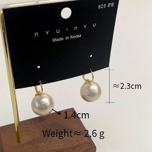 Detailed macro of gold ring earrings with large white pearls and 925 silver posts