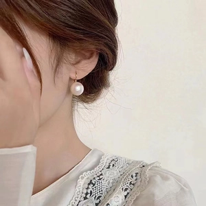 Detailed view of large cotton pearl earrings with gold hooks on a model with lace top