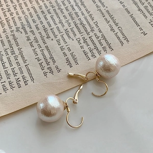 Detail of vintage champagne cotton pearl earrings on retro paper with gold hooks