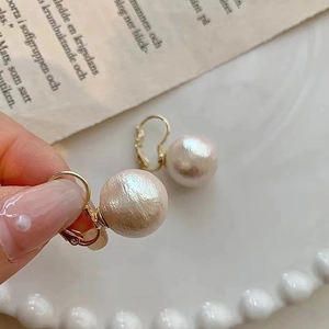 Detail shot of vintage 12mm cotton pearls with textured finish on gold earring hooks