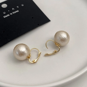 French style 12mm cotton pearl earrings with gold hooks on a minimalist white ceramic plate