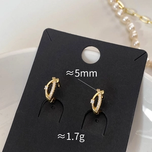 Détails de boucles d'oreilles croisées plaquées or avec zircons et décor de perles