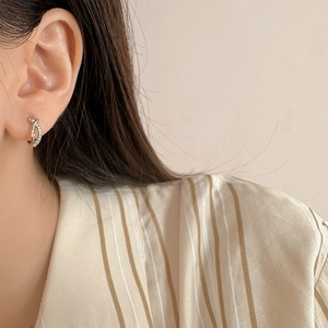 Élégantes boucles d'oreilles créoles croisées argentées avec cristaux sur un mannequin