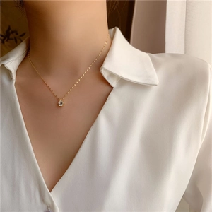 Gros plan sur le collier minimaliste plaqué or avec un pendentif en zircon scintillant