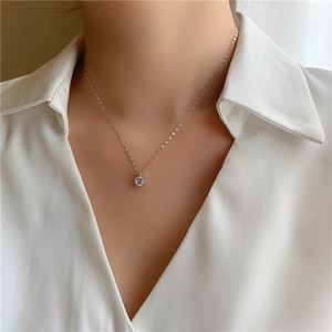 Gros plan d'un collier argenté minimaliste avec pendentif solitaire en zircon sur modèle