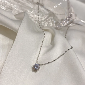 Élégant collier en argent avec pendentif solitaire brillant sur un tissu en soie blanc