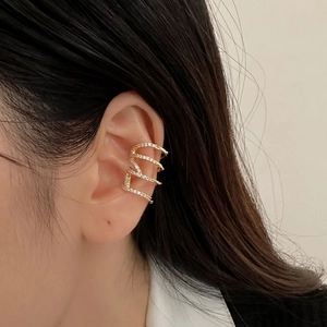 Close-up of golden multi-layer ear cuff with shimmering zircons on a model ear