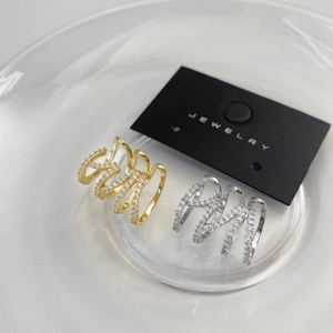 Detail of multi-layer gold and silver rings with cubic zirconia in a glass container