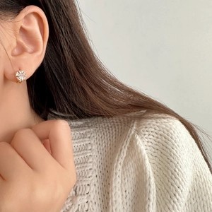Elegant gold flower hoop earrings with sparkling white zircons worn by a model