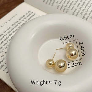 Macro detail of gold-plated double ball earrings with 1.3cm and 0.9cm metallic beads