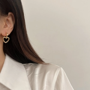 Boucles d'oreilles cœur évidé plaqué or 18 carats portées avec chemise en satin