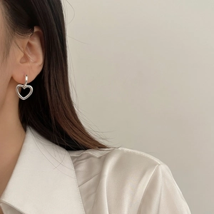 Boucles d'oreilles cœur argentées minimalistes portées par un mannequin en satin
