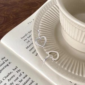 Vue détaillée de boucles d'oreilles cœur argentées posées sur une assiette et un livre ancien