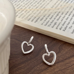 Détail de boucles d'oreilles cœur évidé en argent 925 sur un livre et table en bois