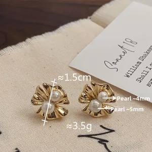Détail de boucles d'oreilles fleurs dorées de 1,5 cm avec perles de nacre