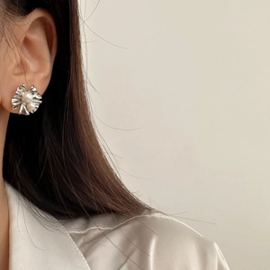 Gros plan de boucles d'oreilles fleurs en métal plissé argenté avec deux perles