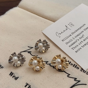 Détail macro de boucles d'oreilles pétales plissés avec perles brillantes dorées et argentées