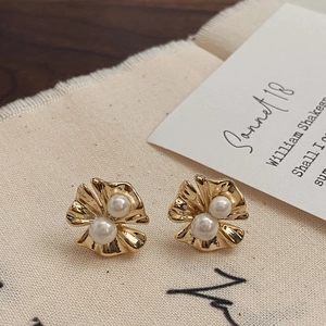Vue macro de boucles d'oreilles fleurs plissées dorées avec perles sur carte vintage