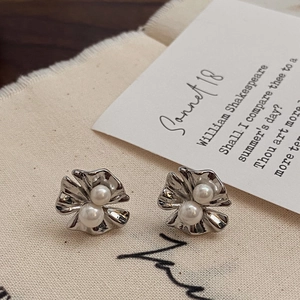 Gros plan de boucles d'oreilles fleur argentée avec perles sur tissu de style rétro