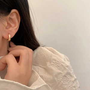 Elegant gold shell crossover hoop earrings worn by a model for a minimalist daily look