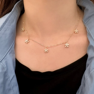 Goldene Blumenkette mit fünf funkelnden Zirkonia-Anhängern, getragen an einer feinen Kette
