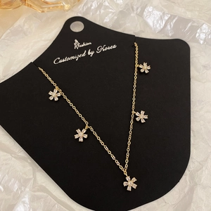 Elegante goldene Blumenkette mit fünf funkelnden Zirkonia-Anhängern auf Schmuckkarte