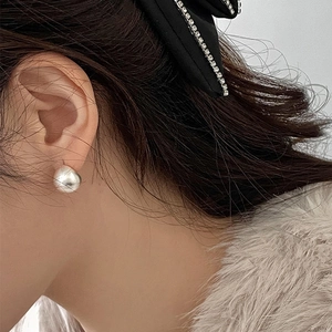 Close-up of polished silver teardrop earring worn by a model in elegant styling