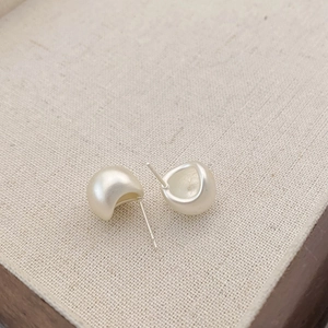 Macro detail of matte silver teardrop earrings showing fine frosted texture on linen