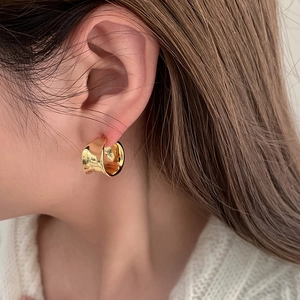 Chic irregular wide C-shape gold-plated hoop earrings worn by a model in close-up shot