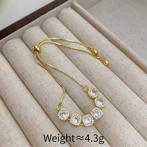 Détail d'un bracelet doré ajustable orné de six pierres de zircone cubique brillantes