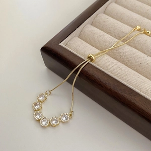 Gros plan du bracelet doré réglable orné de six pierres de zircon rondes et brillantes